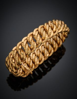 gros plan d'un bracelet en or sur une surface noire