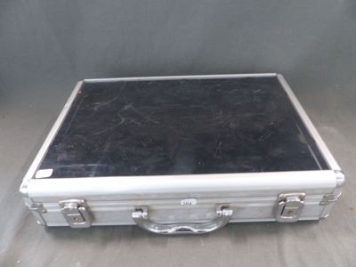 une valise argentée au couvercle noir posée sur une table