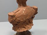 a clay bust of a man on a wooden stand