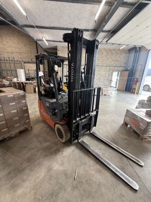 un chariot élévateur dans un entrepôt où se trouvent des palettes et des cartons