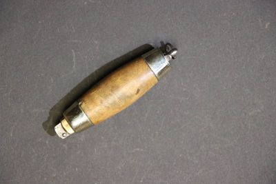 un petit objet métallique avec une poignée en bois sur une table