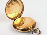 a gold pocket watch with a keychain on a white surface