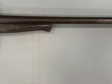 un vieux pistolet accroché au mur, muni d'une crosse en bois