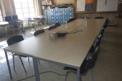 une longue table sur laquelle est posé un ordinateur portable, au milieu d'une pièce