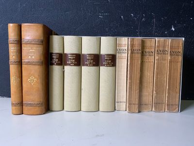 Plusieurs vieux livres sont alignés sur une étagère devant un mur noir