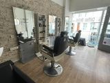 une photo d'un salon de coiffure avec des fauteuils et un miroir