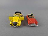 two toy cars with people in the back of them on a gray surface