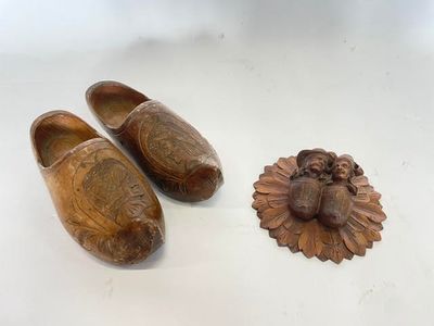 une paire de sabots en bois ornés d'une tête de lion sur le dessus