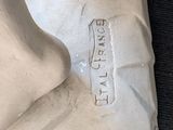 a white statue of a person with a foot on a table