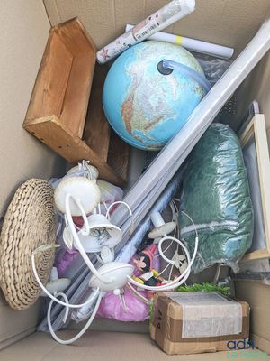 a cardboard box filled with assorted items including a baseball bat, a globe, and other items
