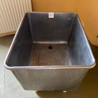 une grande cuve métallique posée par terre à côté d'un radiateur