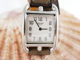 a watch sitting on top of a shell with a shell in the background