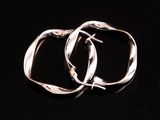 une paire de boucles d'oreilles créoles en argent sur fond noir