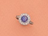 gros plan d'une bague avec une pierre bleue entourée de diamants
