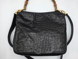 un sac en cuir noir avec des anses en bambou sur fond blanc