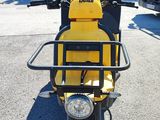 a yellow moped parked in a parking lot with a bus in the background