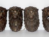 trois têtes de lion en bronze sont posées sur une surface blanche