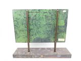 a green metal object on a stand on a white surface