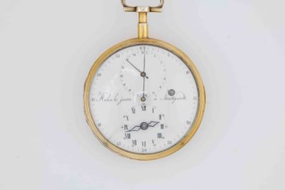 a gold pocket watch hanging on a white wall