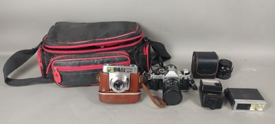 un appareil photo, un étui pour appareil photo, un appareil photo et d'autres objets disposés sur une table