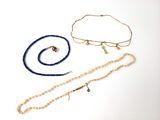Deux colliers et un bracelet sont posés sur une surface blanche
