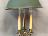 une lampe posée sur une table, munie d'un abat-jour vert