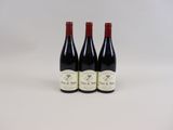 trois bouteilles de vin posées sur une table blanche
