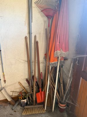 un tas de balais et de râteaux près d'un mur