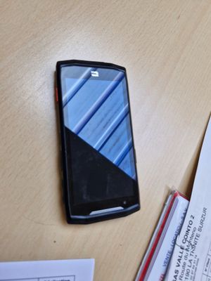 un téléphone portable posé sur une table, à côté d'une pile de papiers