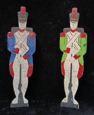 two wooden toy soldiers are standing next to each other on a black surface