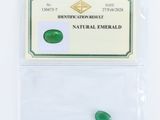 des pierres précieuses vert émeraude dans un sachet transparent posé sur une surface blanche