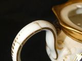 a white and gold teapot with a blue and gold lid