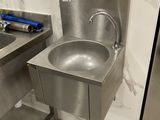 a stainless steel sink in the corner of a bathroom