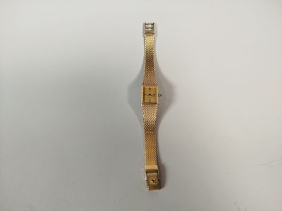 gros plan d'une montre en or sur une surface blanche