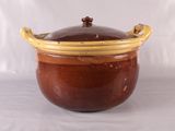 un pot marron et jaune avec un couvercle, posé sur une surface blanche