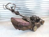 a small lawn mower sitting on the ground in front of a garage door