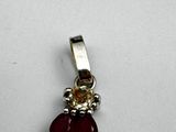 a close up of a red and gold pendant on a white surface