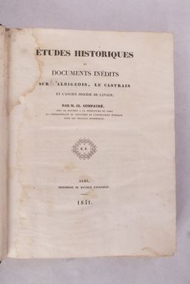 un vieux livre posé sur une table à côté d'un mur blanc