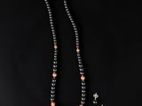 un collier de perles noires, agrémenté de perles de corail et d'argent sur fond noir