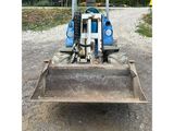 a blue tractor that is parked in the dirt
