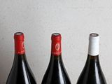 three bottles of red wine are lined up on a table