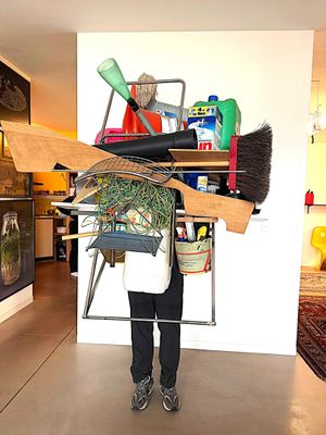 a man that is standing in front of a shelf with a broom on it