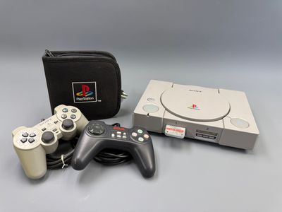 une console de jeux et deux manettes placées l'une à côté de l'autre