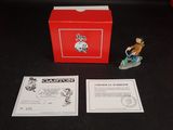 une petite figurine représentant un homme sur un skateboard devant une boîte rouge