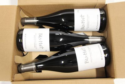 three bottles of wine in a cardboard box on a table