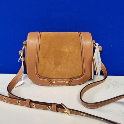 a brown leather cross body bag on a white table