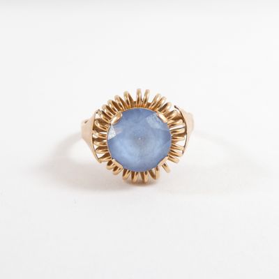 gros plan d'une bague en or avec une pierre bleue