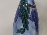 a blue vase with purple flowers on it sitting on a table