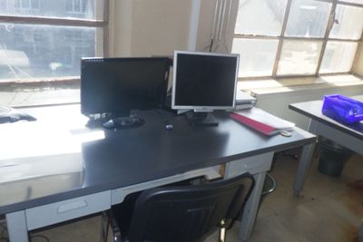 deux écrans d'ordinateur posés sur un bureau devant une fenêtre