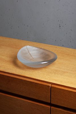 a glass plate with a leaf on top of a wooden dresser